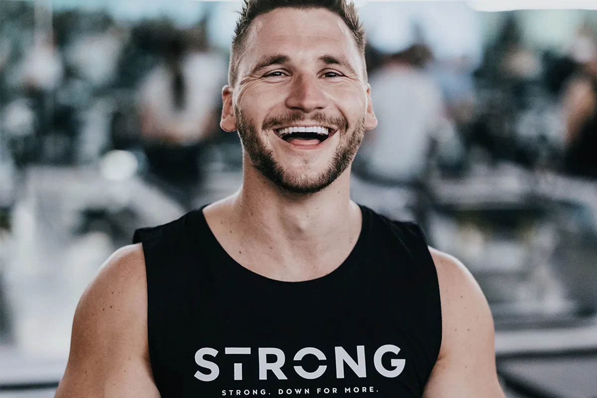 A smiling man in a STRONG Pilates singlet at the studio